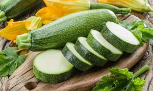 Cukinia i jej kwiaty na desce. Czy pies może jeść cukinie? Tak, to zdrowy dodatek do diety czworonoga.