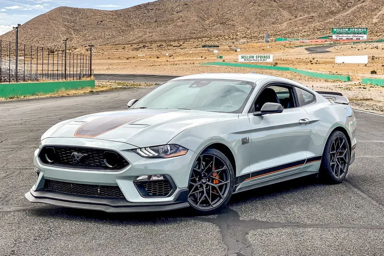Szary Ford Mustang Mach 1 na torze wyścigowym. Zastanawiasz się, ile kosztuje koń Mustang? Ten model to marzenie wielu kierowców.